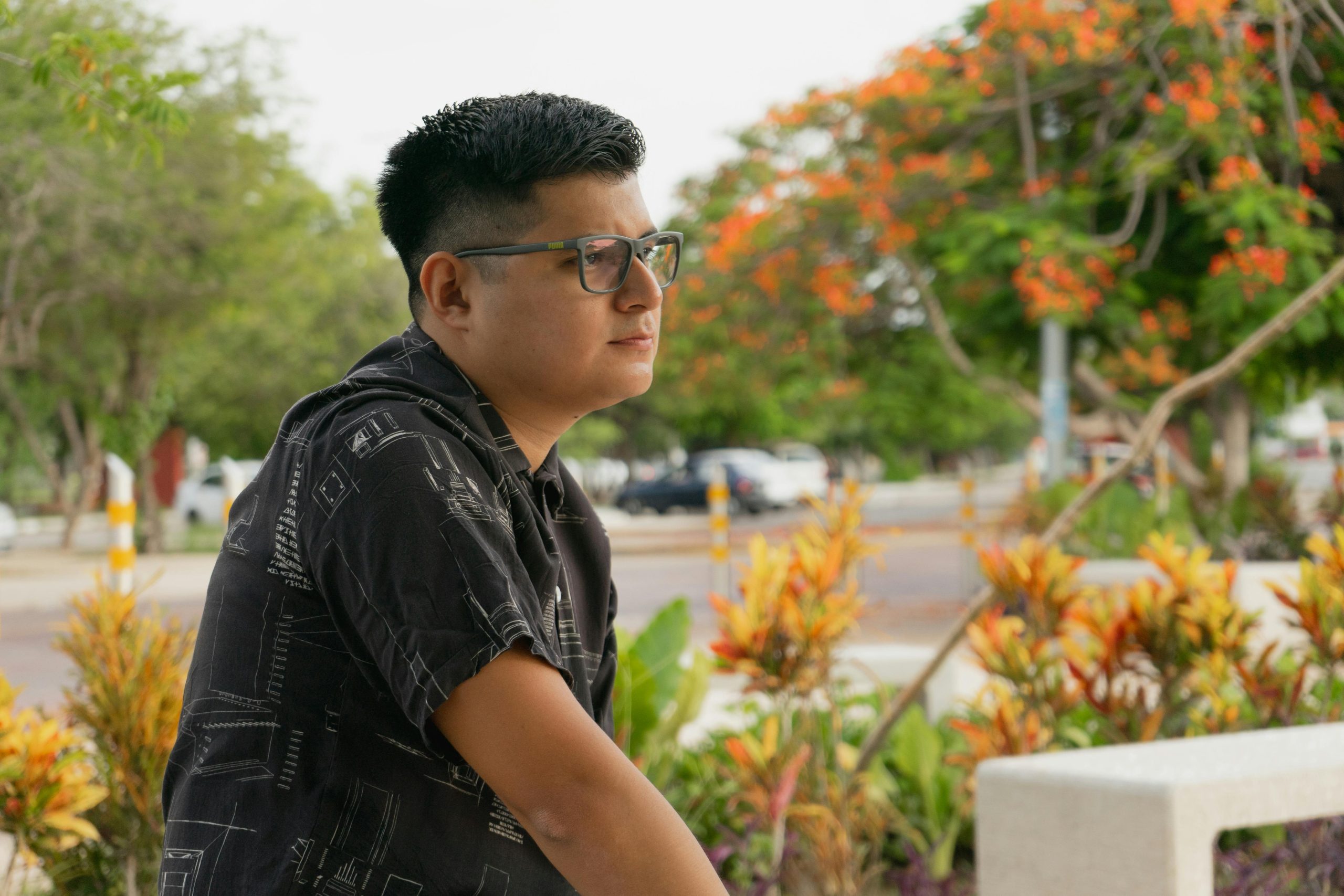 Relaxed man with glasses in a Yucatan park surrounded by vibrant flora.